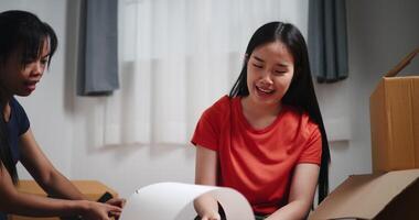 Handheld shot, Two Asian women are helping to assemble a floor lamp in the living room in new home. Moving to a new home concept video