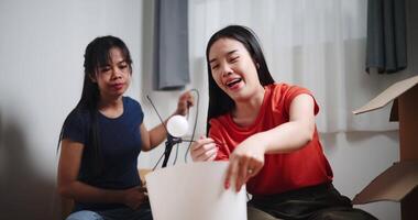 Handheld shot, Two Asian women are helping to assemble a floor lamp in the living room in new home. Moving to a new home concept video