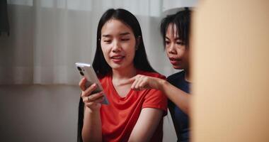 Handheld dolly shot, Two Asian siblings sit on the floor, search for interior design ideas on their phone, and discuss decorating a room in new home. Moving and lifestyle concepts. video