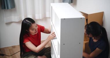 Handheld high angle view shot, Two siblings are happily chatting while assembling furniture together in the living room of their new house. Moving to a new home concept video