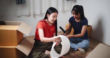 Handheld high angle view shot, Two Asian women are helping to assemble a floor lamp in the living room in new home. Moving to a new home concept video