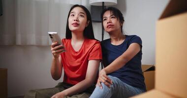Handheld selective focus shot, Two Asian siblings sit on the floor, search for interior design ideas on their phone, and discuss decorating a room in new home. Moving and lifestyle concepts. video