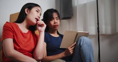 Handheld low angle view shot, Two Asian women are happily chatting and making a shopping list to decorate a room in new home. Moving to a new home concept video