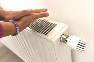 hand adjusting radiator temperature using thermostat. Home with central heating. photo