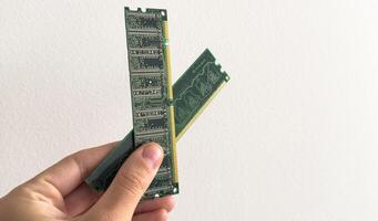 Man holding up a RAM module, or random access memory, in which all storage locations can be rapidly accessed in the same amount of time used by a computer operating system, on white photo