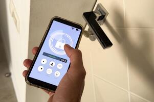 smart house, home automation, device with app icons. Man uses his smartphone with smarthome security app to unlock the door of his house. photo