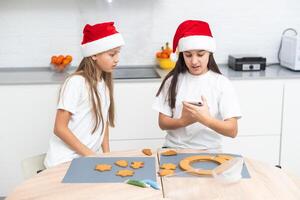 Two girls sisters are playing around in the kitchen after making Christmas cookies, they draw with flour on the table and on their faces. Christmas, New Year concept photo