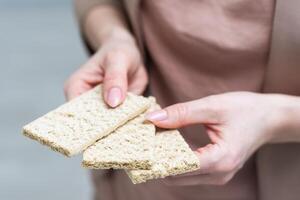 Hand with salty cracker, crispy appetizer, rectangle shape cookie. Isolated on white background. photo