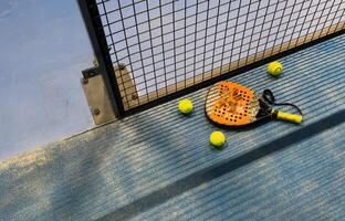 padel racket and yellow balls placed on court near net photo