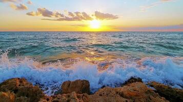 The sun setting over the ocean with waves crashing on the rocks photo