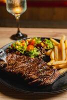 Lunch featuring a steak filet, salad, and French fries, elegantly presented on a table. photo