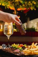 Lunch featuring a steak filet, salad, and French fries, elegantly presented on a table. photo