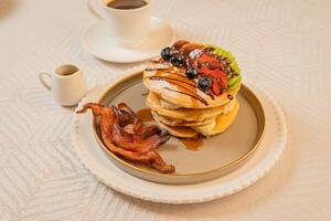 A breakfast of pancakes drizzled with honey, served with crispy bacon photo