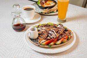 Fruit crepes with chocolate and maple syrup for breakfast photo