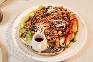 Fruit crepes with chocolate and maple syrup for breakfast photo
