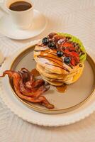 A breakfast of pancakes drizzled with honey, served with crispy bacon photo