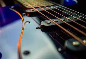 Abstract photo of an electric guitar and its parts macro photo. Music wallpaper and banner for string music album. High quality photo guitar in dark with light reflected in the lacquered surface.