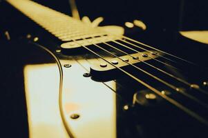 Abstract photo of an electric guitar and its parts macro photo. Music wallpaper and banner for string music album. High quality photo guitar in dark with light reflected in the lacquered surface.