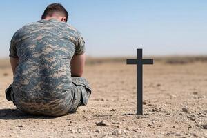 A soldier in uniform kneeling in the desert photo