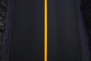 An empty road with a yellow line on it photo
