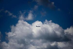 A plane is soaring through the cloudy, vibrant blue sky above photo