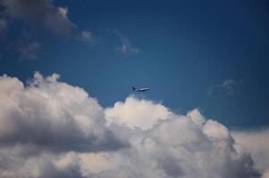 A plane is soaring through the cloudy, vibrant blue sky above photo