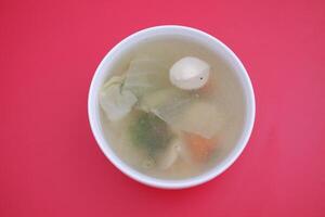 A bowl of soup on a red table photo