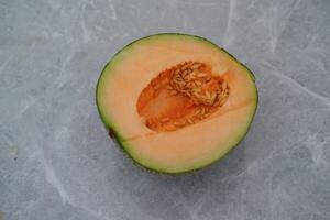 half cantaloupe melon on a marble background photo