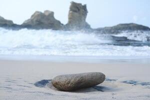 A smooth stone rests on the sandy beach photo