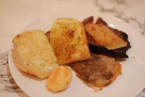 French toast with fried meat and potato chips on a white plate. photo