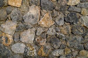 Unique patterns of natural stones create a rustic and textured wall in a tranquil outdoor setting photo