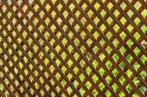 Intricate wooden lattice casting shadows in a lush garden setting during a bright afternoon photo