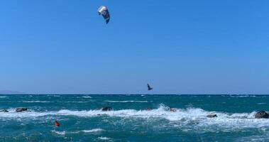 Sun-kissed kitesurfers ride the waves on a vibrant blue ocean during a windy afternoon by the shore photo