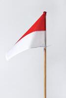 The red and white Indonesian flag with a wooden pole is on a white background photo