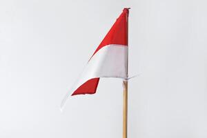 The red and white Indonesian flag with a wooden pole is on a white background photo