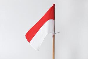 The red and white Indonesian flag with a wooden pole is on a white background photo