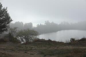 Foggy morning in autumn landscape with lake and mist photo