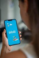 Prague, Czech republic - May 2, 2024. Woman holding iPhone with logo of application Wolt on the screen, using mobile application . High quality photo