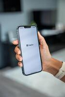Prague, Czech republic - May 2, 2024. Woman holding iPhone with logo of application CapCut on the screen, using mobile application for business home. High quality photo