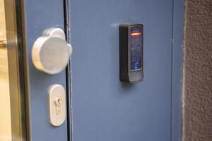 Close up view of door with electric lock with reader of entry system mounted on a house wall. High quality photo