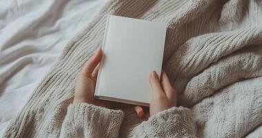 Close-up mockup of woman hands holding a blank white book. Ideal for book cover design, branding, and product display. Minimalist and cozy scene photo