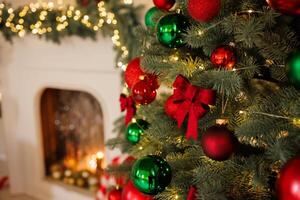 Christmas red bow on a tree, close-up, against the background of a fireplace, stylish New Year photo
