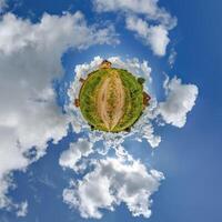 tiny planet in blue sky with clouds of old abandoned ruined church. Transformation of spherical 360 panorama in abstract aerial view. photo