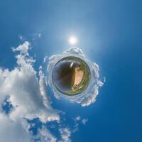 simple little tiny planet without buildings in blue sky with sun and beautiful clouds. Transformation of spherical panorama 360 degrees. Spherical abstract aerial view. Curvature of space. photo