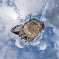 tiny planet in blue sky with clouds of old abandoned ruined church. Transformation of spherical 360 panorama in abstract aerial view. photo