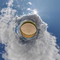 simple little tiny planet without buildings in blue sky with sun and beautiful clouds. Transformation of spherical panorama 360 degrees. Spherical abstract aerial view. Curvature of space. photo