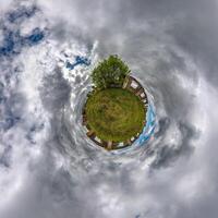 tiny planet in blue sky with clouds of old abandoned ruined church. Transformation of spherical 360 panorama in abstract aerial view. photo