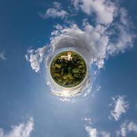 simple little tiny planet without buildings in blue sky with sun and beautiful clouds. Transformation of spherical panorama 360 degrees. Spherical abstract aerial view. Curvature of space. photo