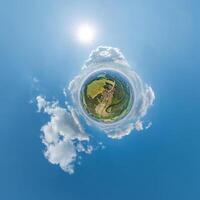 simple little tiny planet without buildings in blue sky with sun and beautiful clouds. Transformation of spherical panorama 360 degrees. Spherical abstract aerial view. Curvature of space. photo