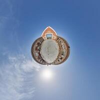 tiny planet in blue sky with clouds of old abandoned ruined church. Transformation of spherical 360 panorama in abstract aerial view. photo